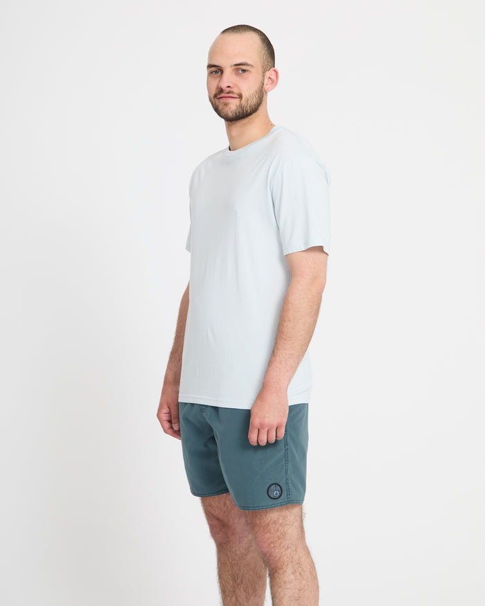A man with a short beard and close-cropped hair stands sideways to the camera, wearing Volcom Men's Center Trunks 17 against a plain white background.