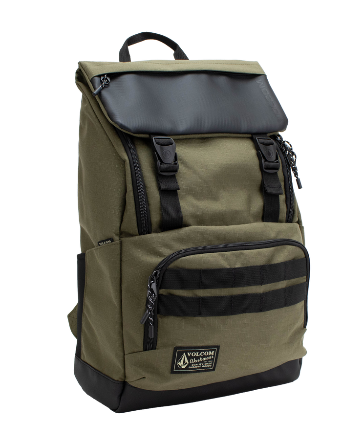 Men’s Charter Ruck Backpack by Volcom in olive green features a black flap, top handle, front zip pocket, and patch label. This workwear-inspired backpack has black straps, side pockets, and a rectangular silhouette shown against a white background.