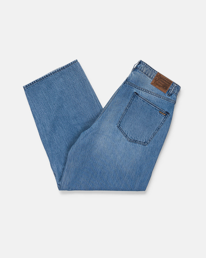 A pair of Volcom Men's Chillow Denim Vs in blue, folded neatly with a visible back pocket and brown leather patch on the waistband, displayed on a white background.
