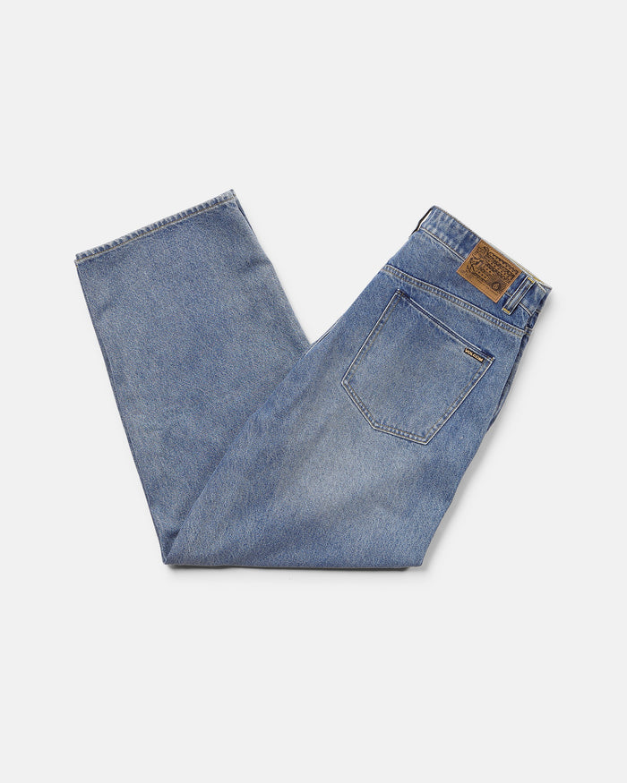 A pair of Volcom Men's Chillow Denim Pants in Euro Light Blue, low-rise and neatly folded with a brown leather patch on the waistband and a visible back pocket, set against a plain white background.