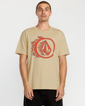 A man stands against a plain white background wearing the Volcom Men's Circle Stone Short Sleeve Tee, a classic fit crew neck made from premium ring spun cotton with a red geometric logo surrounded by flames on the front.
