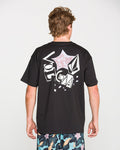 A person with short, light brown hair is seen from behind wearing the Volcom Men's Concrete Jungle Short Sleeve Tee in black—crafted from heavyweight ringspun cotton and showcasing bold graphic designs along with "Volcom" printed on the back. They are also sporting vibrant, patterned shorts.