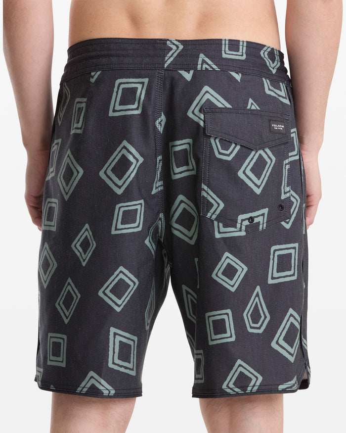 A person is shown from the back wearing Volcom Men's Contact Scallop Stoney 19 black shorts with a green geometric square pattern and a buttoned flap pocket on the right side.