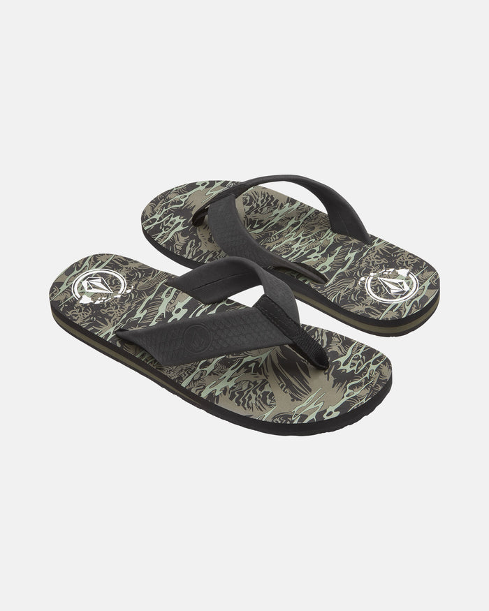 The Volcom Men's Daycation 2 Hawaii Sandals feature black straps and patterned soles with abstract green, beige, and black designs, plus a white circular logo near the heel on each sandal.