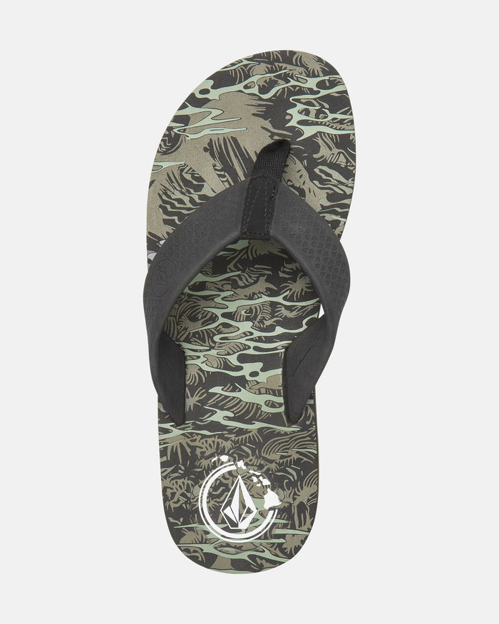The Volcom Men's Daycation 2 Hawaii Sandal features a black strap, green camo-patterned sole, and a white geometric logo near the heel.
