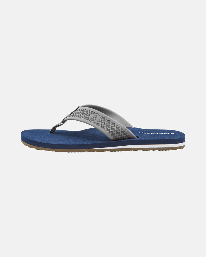 The Volcom Men's Daycation 2 sandal features a blue molded EVA footbed, gray textured thong strap, and brown rubber outsole, displayed on a plain white background.