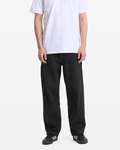 A person wearing Volcom Men's Dialed Work Pants in black pinstripes, a plain white T-shirt, and black Adidas sneakers with white stripes stands against a plain white background. The person's head is not visible.