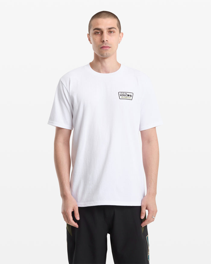 A man with short hair faces the camera, wearing the Volcom Men's Dispatch Short Sleeve Tee in white with a small black logo on the left chest and black pants, standing against a white background.