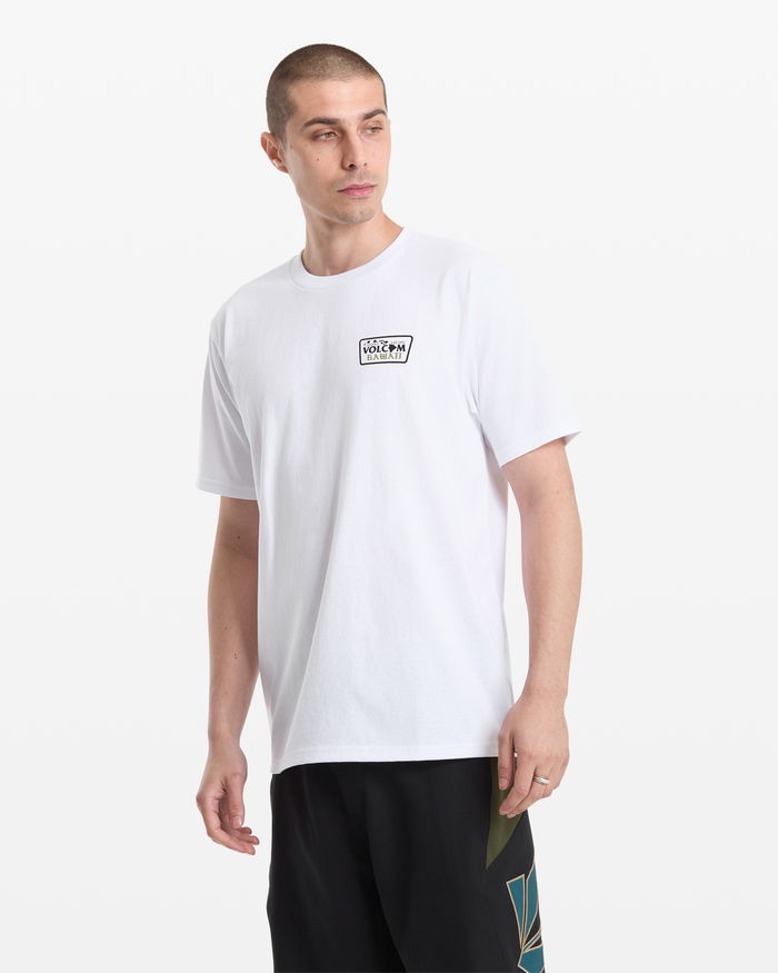 A man with short hair wears the Volcom Men's Dispatch Short Sleeve Tee, featuring a small rectangular chest logo, and black shorts. He stands against a plain white background, looking slightly to his left.