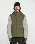 A man with a mustache wears a black beanie, black gloves, and the Volcom Men’s Double Insulated Jacket—an olive green and gray technical outerwear piece featuring recycled warmth—as he stands facing forward against a plain white background.