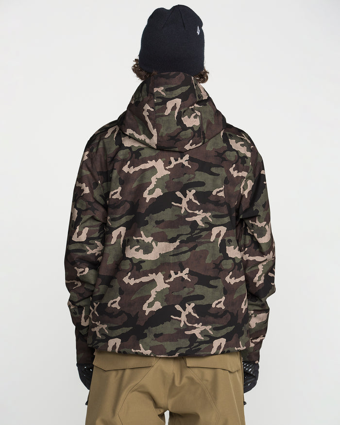 A person wearing a black beanie, tan pants, and the Volcom Men’s Double Insulated Jacket in a camouflage pattern with recycled insulation stands with their back to the camera against a plain white background.