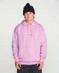 A person wearing a black knit beanie and the Volcom Men’s Essential Hoodie in light pink—crafted from soft cotton-poly fleece with a front pocket—stands facing forward against a plain white background, hands relaxed at their sides.