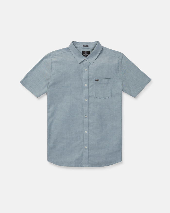 The Volcom Men's Everett Oxford II Short Sleeve Shirt, shown on a plain white background, features a light blue color, classic fit, stretch-woven comfort, button-up front, and left chest pocket for everyday versatility and timeless style.