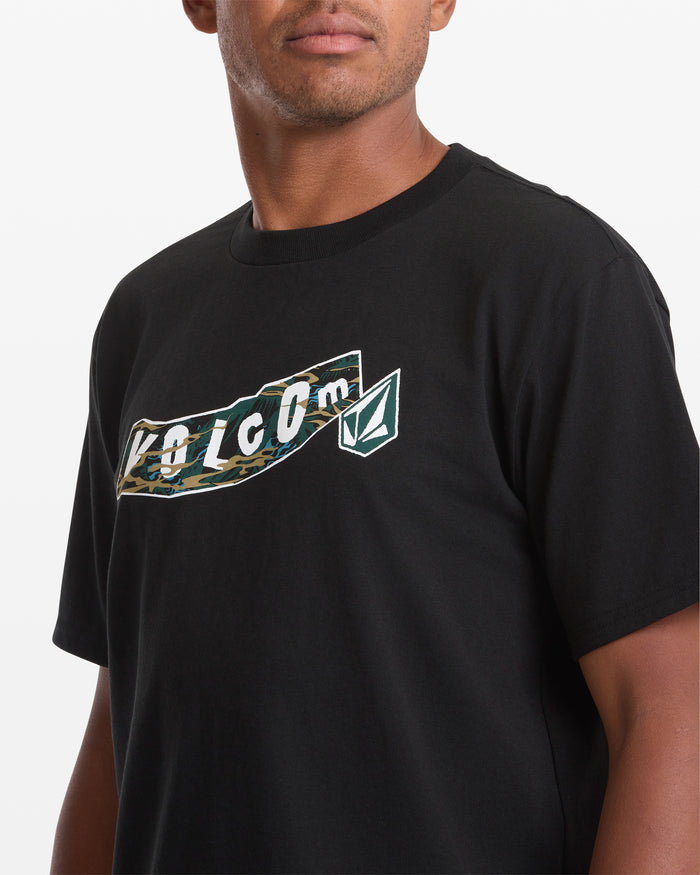 A man wearing the Volcom Men's Featured Artist Parillo Short Sleeve Tee, featuring a camo-patterned Volcom logo and text on the chest, shown from the shoulders up and facing slightly to the side.