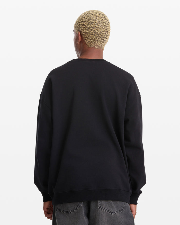 A person with short, curly blond hair is shown from the back wearing the Volcom Men's Featured Artist Seth Conboy Crew and dark gray jeans against a plain white background.