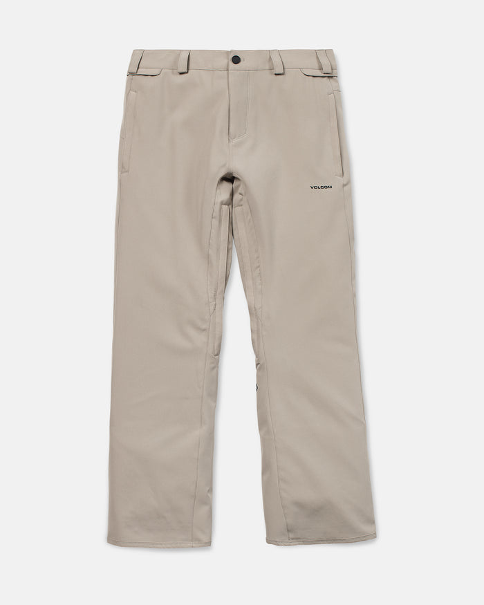 Volcom Men’s Freakin Snow Chino Pants in beige, featuring a straight-leg cut with belt loops, front button closure, side pockets, and a small embroidered Volcom logo on the upper left thigh. Shown laid flat on a white background, these waterproof and breathable snowboard pants are designed for men and offer classic chino style combined with functional performance for winter conditions.