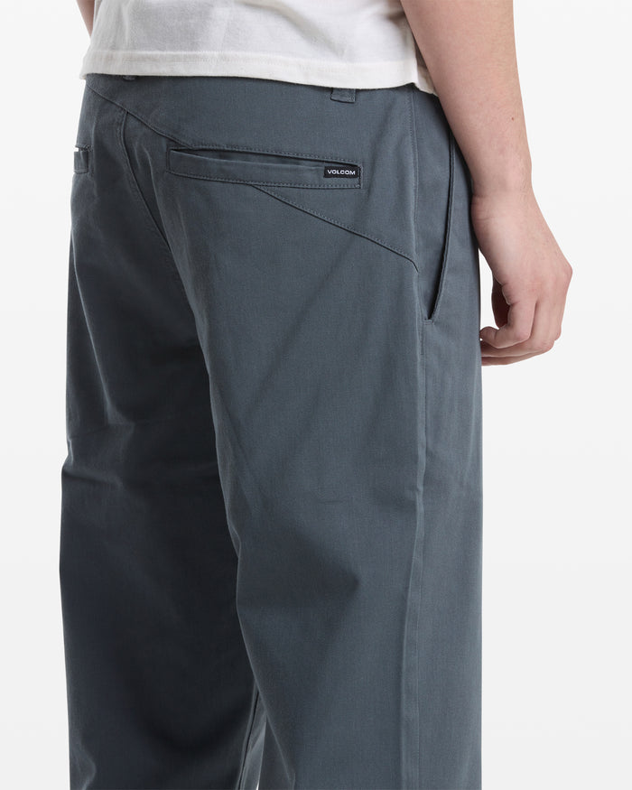 A man, seen from behind at an angle, wears a white shirt and gray Volcom Men's Frickin Modern Stretch Pants.