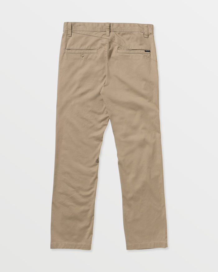 The Men’s Frickin Modern Stretch Pants by Volcom are shown from the back in tan khaki, featuring two back pockets, belt loops, and a straight leg cut. Crafted from recycled polyester for sustainable comfort, these modern pants are displayed against a plain white background.