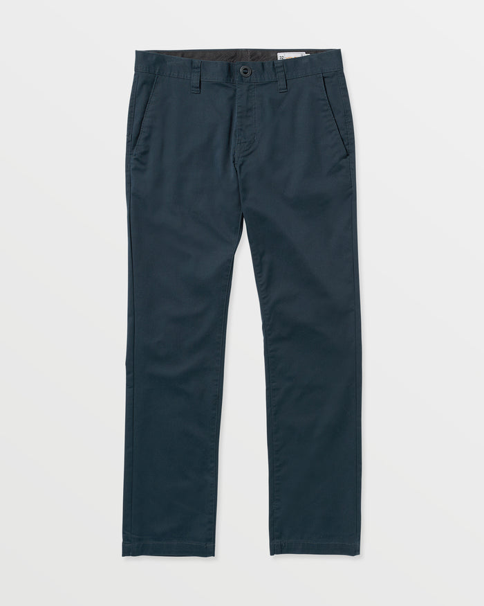 The Volcom Men's Frickin Modern Stretch Pants are slim-fit dark navy blue twill pants with side pockets, button and zip closure, and belt loops, shown on a white background.