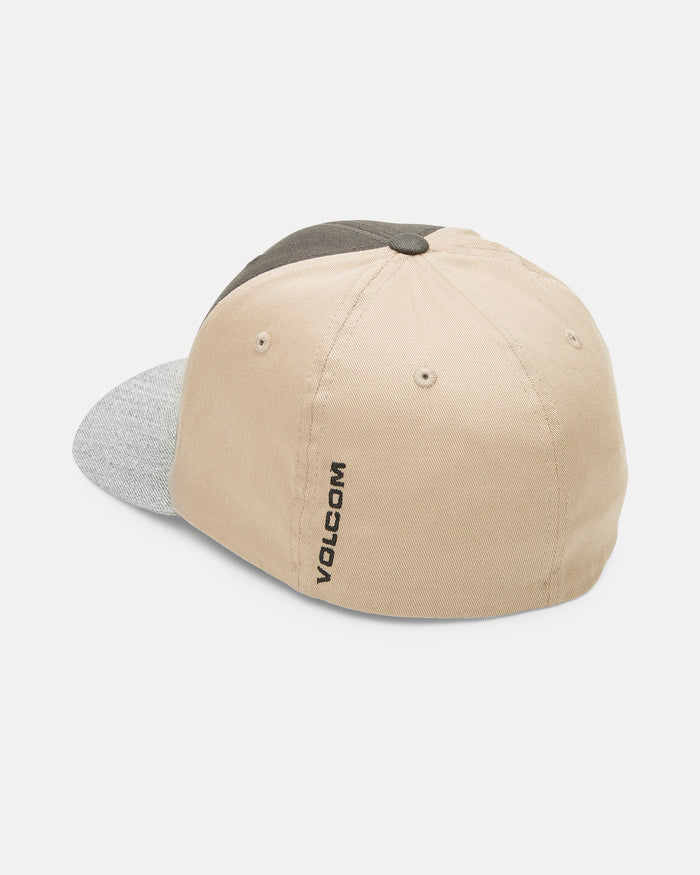The Volcom Men's Full Stone Heather Flexfit Hat features six beige and gray panels, a dark green top button, two metal eyelets, and black "VOLCOM" embroidery on the back beige fabric.