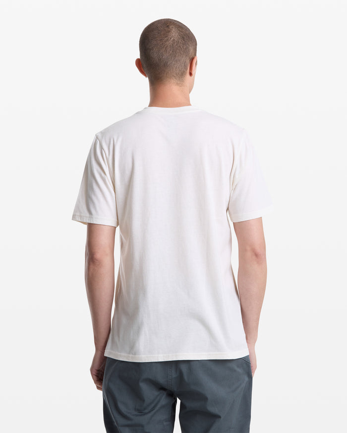 A person with short hair is shown from the back, wearing a Volcom Men's Giddy Up Short Sleeve Tee in white and gray pants, standing against a white background.