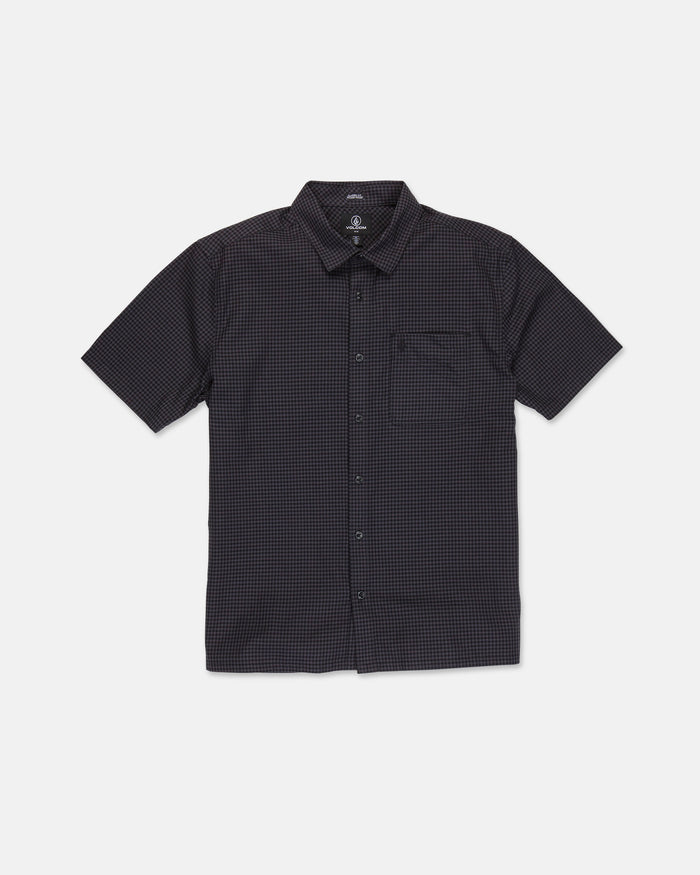 The Volcom Men's Glasnow Short Sleeve Shirt, shown laid flat on a white background, features a black cotton fabric with a subtle small yarn-dyed checkered pattern, button-up front, flat collar, and chest pocket.