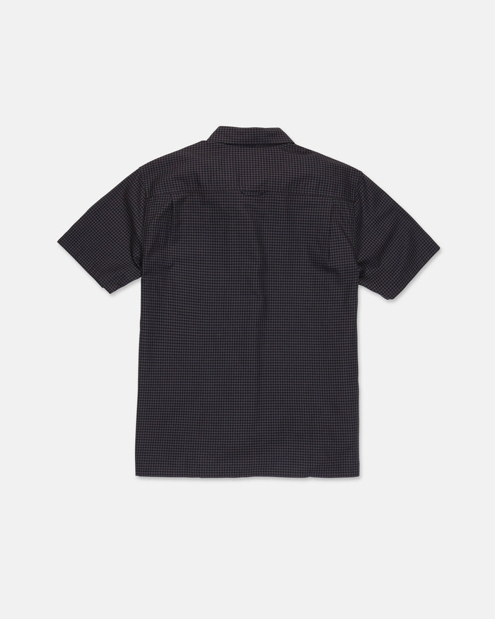 A Volcom Men's Glasnow Short Sleeve Shirt, featuring a small yarn-dyed checkered pattern in dark colors and made from cotton, is laid flat with the back side visible against a white background.