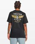 Seen from behind, a person with short dreadlocks wears the Men's Hi Flyer Short Sleeve Tee by Volcom—a black, soft ring spun cotton shirt with a large winged Volcom logo and “Volcom Stone, True To This, Since 1991” in white and yellow.