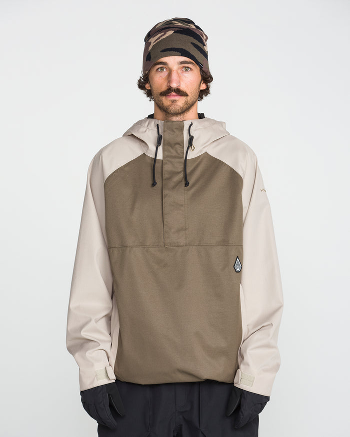 A man with a mustache wears the Volcom Men’s Hossegor 20K Pullover—a two-tone hooded jacket made from recycled V-Science shell with PFAS-free DWR—paired with black gloves and a camouflage beanie, standing against a plain white background.