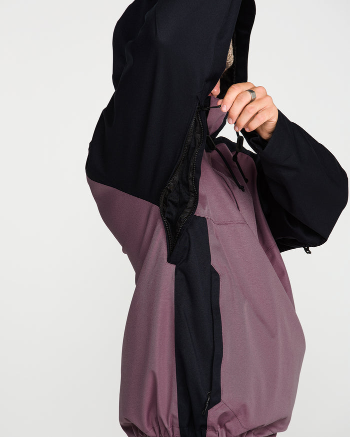 A person wearing the Volcom Men’s Hossegor 20K Pullover unzips the side ventilation opening under the arm, revealing the black interior lining of the recycled V-Science shell; only their arm and hand are visible.