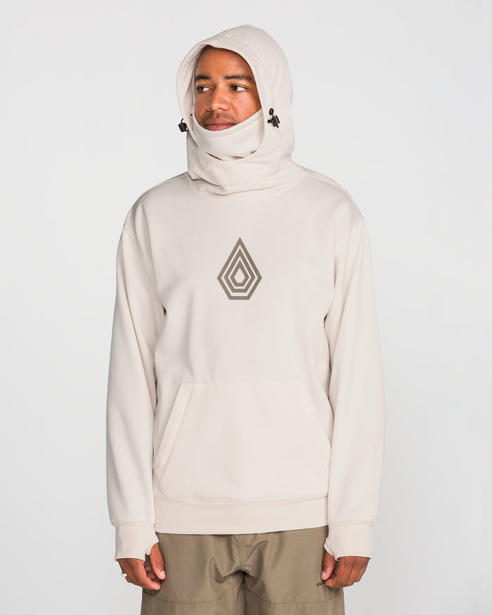 Dressed in the Volcom Men’s Hydro Riding Hoodie—a light beige, hydrophobic fleece sweatshirt with a geometric chest design, high neck, and hood—a person stands against a plain white background.