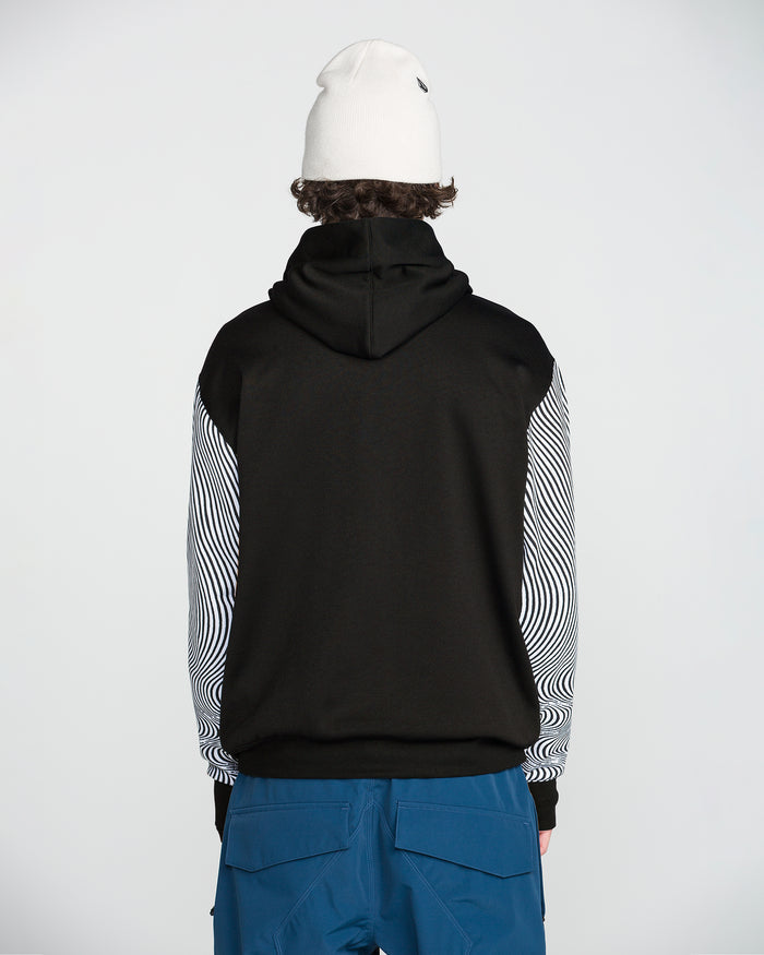 A person is standing with their back to the camera against a plain background, wearing a white beanie, blue pants, and the Volcom Men’s Hydro Riding Hoodie—a black hoodie made from hydrophobic fleece with striped sleeves.