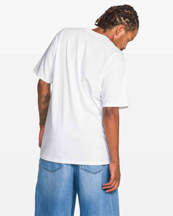 A person with braided hair, wearing the Volcom Men's Hypnotizer Short Sleeve Tee and blue denim shorts, stands facing away from the camera, showing the back of their shirt and head.