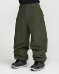 A person wearing Volcom Men’s Lapper Pants in a loose-fitting, dark green style paired with black sneakers, standing against a plain white background. Only the lower half of the body is visible.