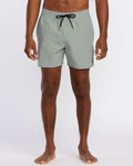 A person stands barefoot in Volcom Men's Lido Solid 16" Trunks, light gray with a black drawstring and small logo on the left leg. The 2-way stretch swim trunks are cropped at the torso; background is plain white.