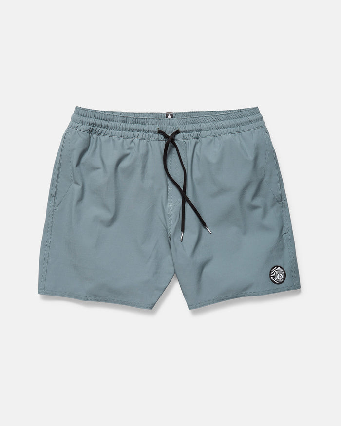 The Volcom Men's Lido Solid 16" Trunk in light blue features an elastic waistband, black drawstring, side pockets, and a small circular patch near the left hem. The shorts are displayed flat on a plain white background.