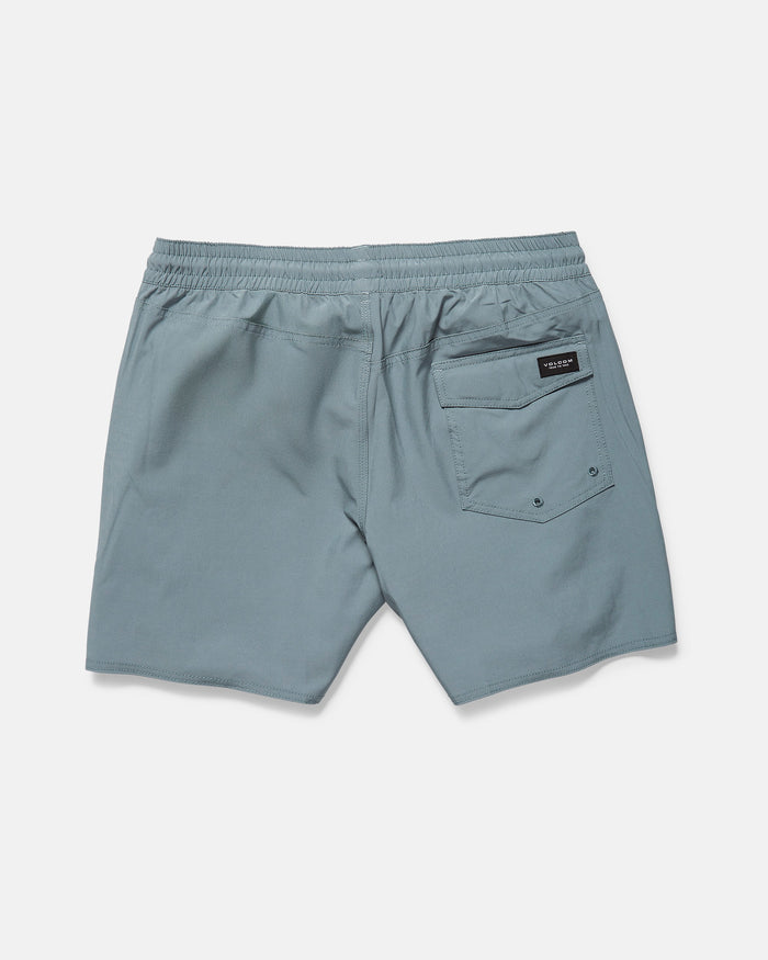 The Volcom Men's Lido Solid 16" Trunk is a light grayish blue boardshort with a 5-inch inseam, elastic waistband, and a single back pocket with black label and metal rivets, shown on a plain white background.