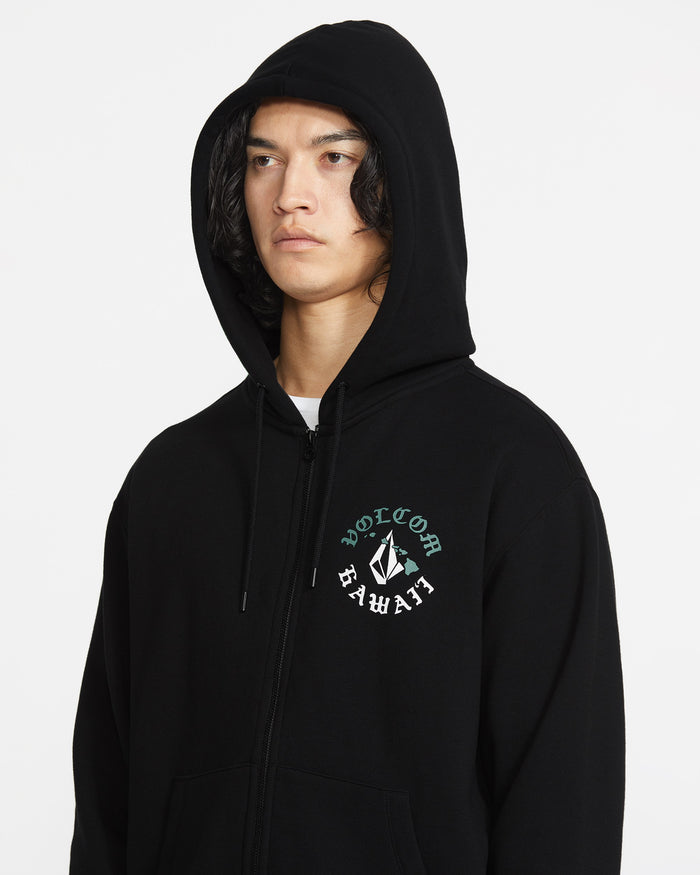 A person wears the Men's Lineage Zip Fleece by Volcom, a black relaxed fit sustainable hoodie with a zip front, hood up, and Volcom Hawaii logo on the left chest. The background is plain white.