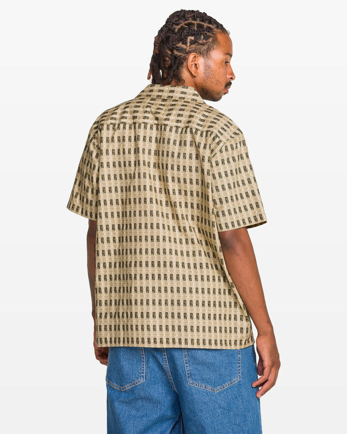 Person wearing a patterned shirt and blue jeans on a white background