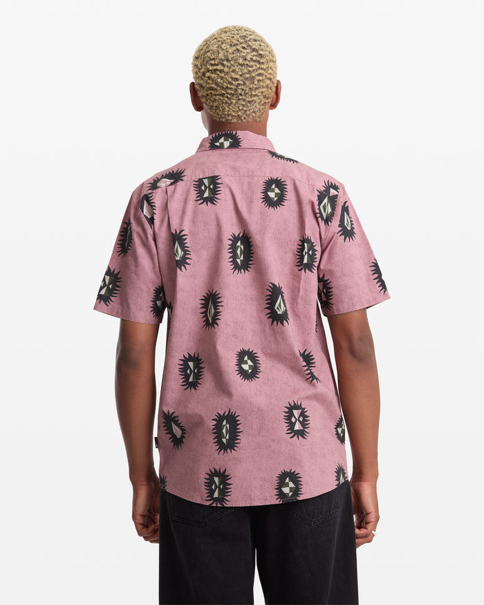 A person with short blond hair, seen from behind, wears the Volcom Men's Markerstone Short Sleeve shirt with a black and white abstract eye print and black pants against a white background.