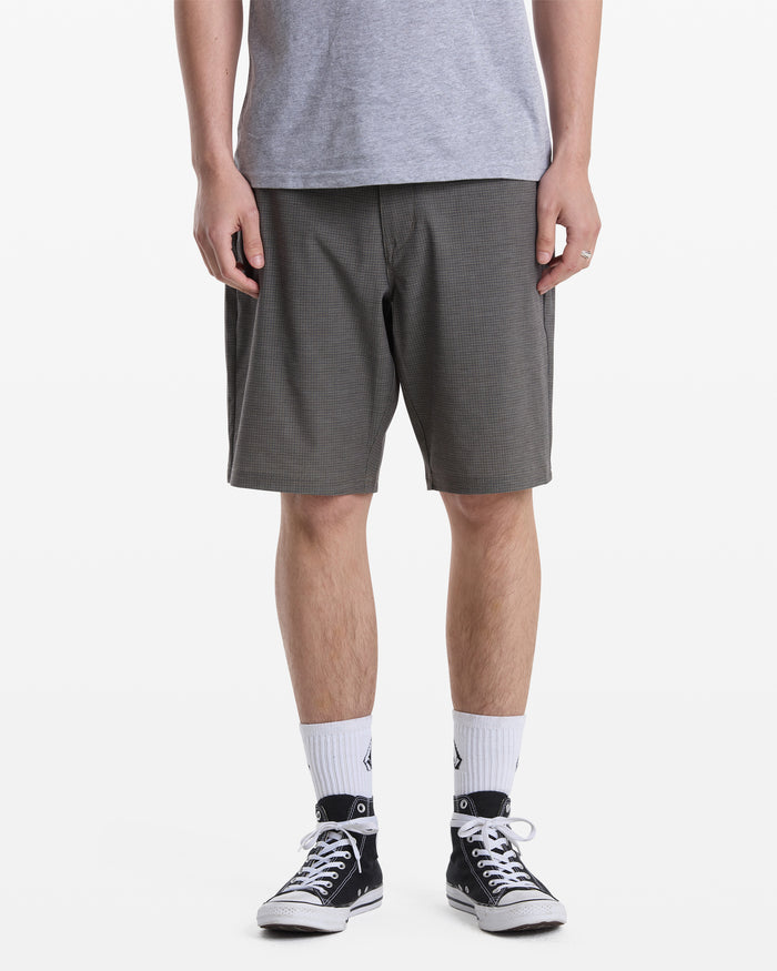 A person models Volcom Men's Mix Frickin Cross Shred Shorts, paired with a gray t-shirt, white crew socks, and black-and-white sneakers against a white backdrop. The head is cropped out of the image.