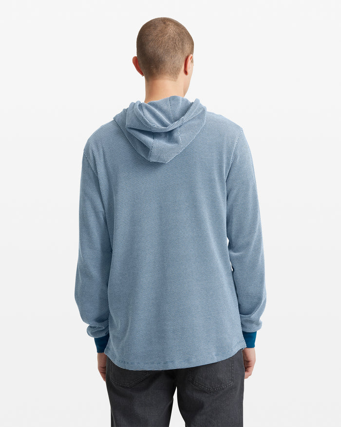 Seen from behind against a plain white background, a person with short hair is wearing the Volcom Men's Murph Thermal Long Sleeve in light blue with dark gray pants.