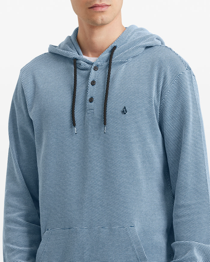 A man wears the Volcom Men's Murph Thermal Long Sleeve—a light blue waffle knit hoodie with black drawstrings, Henley placket, and small chest logo. His face is partially out of frame.