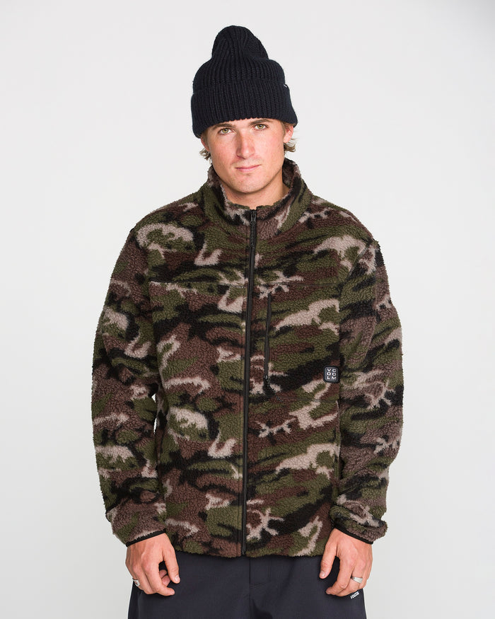A person wearing a black beanie and the Volcom Men’s Nelson Sherpa Full Zip in green camouflage stands against a plain white background, looking directly at the camera with a neutral expression.