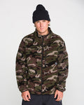 A person wearing a black beanie and the Volcom Men’s Nelson Sherpa Full Zip in green camouflage stands against a plain white background, looking directly at the camera with a neutral expression.