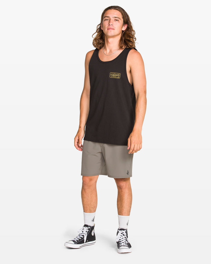 A person with long hair is wearing a black tank top, Volcom Men's Nomoly Elastic Waist Shorts 18", white crew socks, and black high-top sneakers, standing against a plain white background.