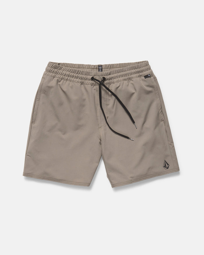 The Volcom Men's Nomoly Elastic Waist Shorts 18" in light brown feature a black drawstring, side pockets, 4-way stretch recycled polyester, and a small Volcom logo near the left hem. Displayed flat on a white background.
