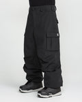 A person is wearing the Volcom Men’s Nwrk 20K Baggy Pants—loose-fitting black cargo pants with multiple pockets, made from recycled shell fabric—paired with black and gray athletic shoes, standing against a plain white background. The relaxed, baggy design of the pants provides a comfortable fit and drapes over part of the shoes.