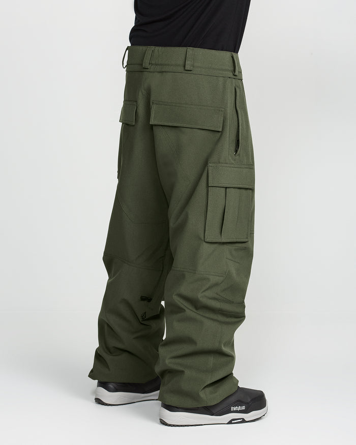 Wearing the Volcom Men’s Nwrk 20K Baggy Pants in olive green with multiple cargo pockets and paired with black sneakers, this look features men’s snow pants that provide a stylishly baggy fit and functional design—set against a plain white background.