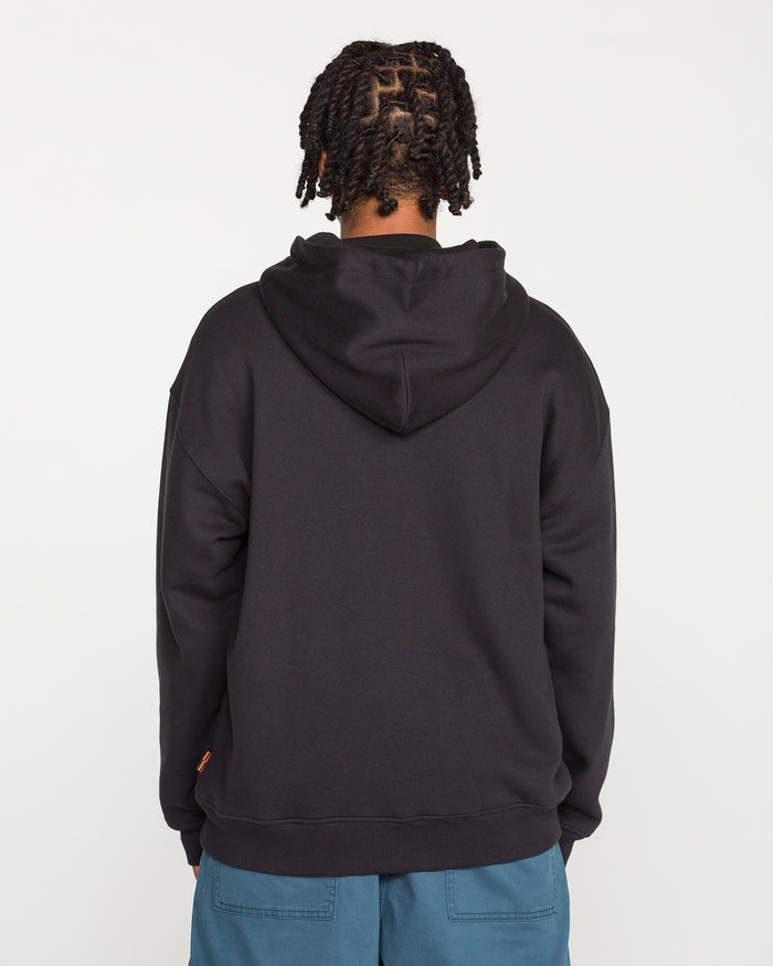 A person with braided hair is shown from the back, wearing the Volcom Men’s On The Hunt Workwear Zip—a black fleece jacket with a cotton waffle thermal lining—paired with blue pants against a plain white background.